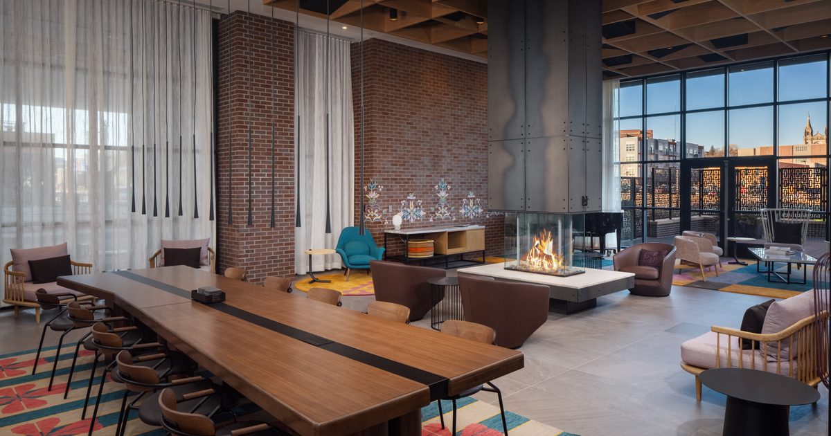 Inside the Canopy in Sioux Falls, a long wooden table surrounded by chairs on a brightly colored carpet