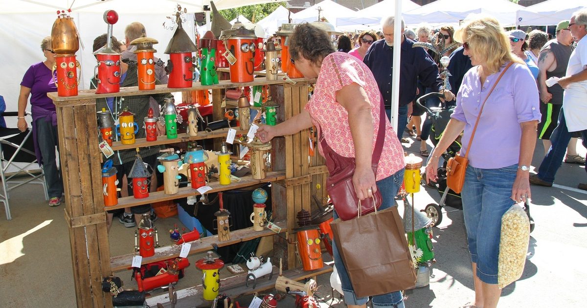 Two women looking at a booth of hand-made items during a Craft show
