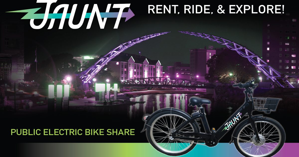 Jaunt - Rent, Ride, & Explore. Public Electric Bike Share. A bike with downtown Sioux Falls in the background at night