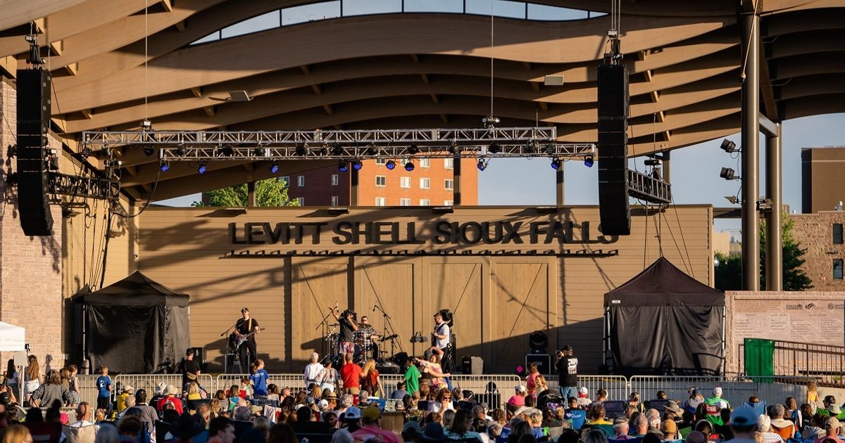 A band performs on stage at Levitt at the Falls in front of spectators.