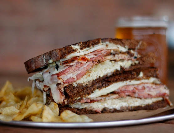 Two halves of a sandwich stacked on top of each other with chips on the side