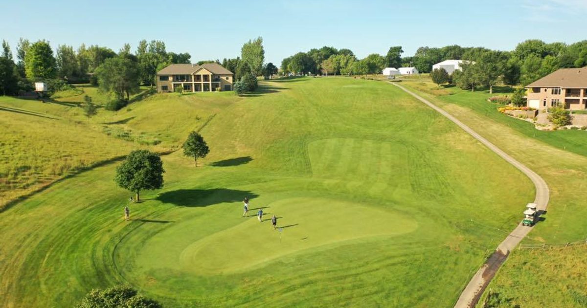 Aerial view of a golf course green as the players approach the pin